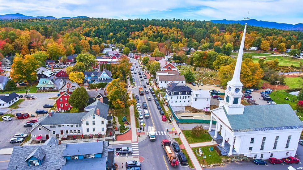 Vacation Travel Innovation Reviews aerial view of Stowe Vermont surrounded by colorful autumn foliage.